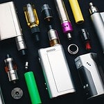 Collection of vape devices, e-cigarettes, and accessories including batteries, tanks, and mods for vaping enthusiasts.